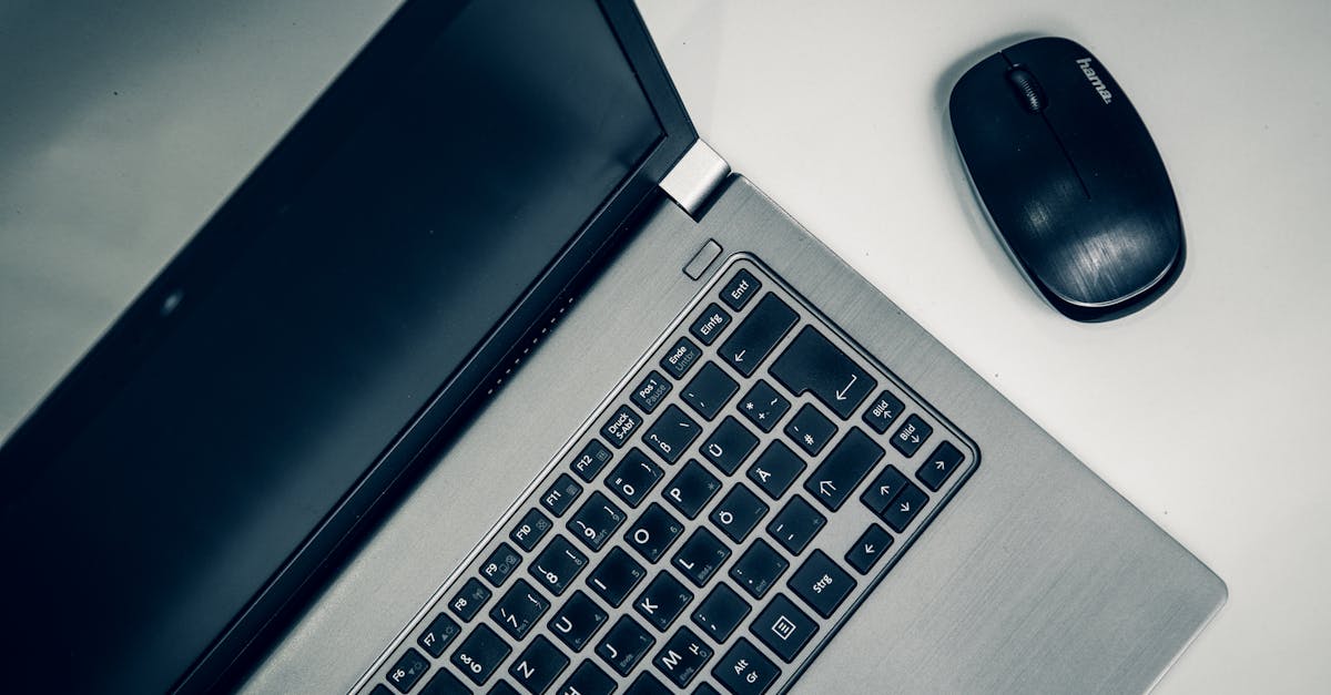 A close-up view of a silver laptop and wireless mouse on a smooth table, ideal for home office setups.